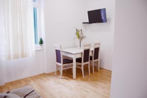une salle à manger avec une table et des chaises blanches dans l'établissement Apartment Anny, à Split