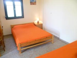 an orange bed in a room with a window at Villa Panorama in Moúdhros