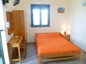 a bedroom with a bed and a desk and a window at Villa Panorama in Moúdhros