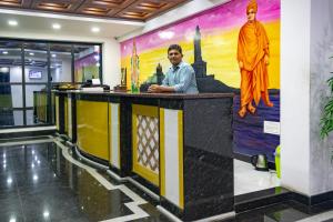 根尼亚古马里Hotel Staar World的站在柜台上的人,墙上挂着壁画