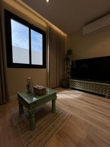a living room with a table and a large screen tv at استديو أنيق كلاسيكي in Riyadh +15 photos