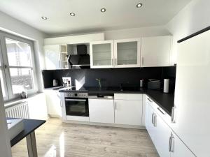 a kitchen with white cabinets and black counter tops at Balance Apartments by M&A - Family Apartment Ferienhaus Dohrenbach in Witzenhausen