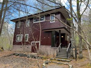 a red house with stairs in the woods at ゲストハウスジャパン浅間湯本 The Guest House Japan Asama in Tsumagoi