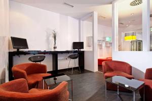 a living room with orange chairs and a table at Wyndham Garden Düsseldorf City Centre Königsallee in Düsseldorf