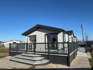 a small house with a porch and some stairs at The Retreat 8 Lodge - Hot tub, WiFi, pet friendly, bath - Golden Palm Resort - Meadow Lakes Caravan & Lodge Hire in Chapel Saint Leonards