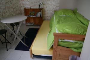 a bedroom with a bed with green sheets and a table at La maison dans le pré in Agon Coutainville