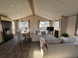 a living room with white furniture and a dining room at The Retreat 8 Lodge - Hot tub, WiFi, pet friendly, bath - Golden Palm Resort - Meadow Lakes Caravan & Lodge Hire in Chapel Saint Leonards