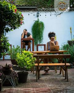 two people sitting at a picnic table with a laptop at Hostal Antique Luna in Santa Ana