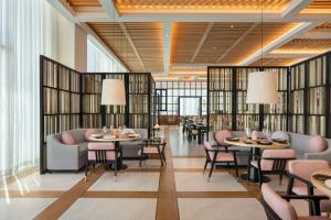 a restaurant with tables and chairs and windows at Andaz Doha, by Hyatt in Doha