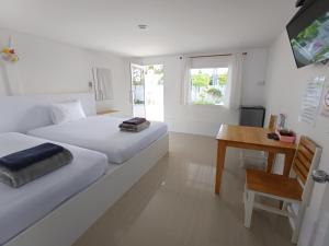 a bedroom with two beds and a table and a desk at Saan Rak Resort in Prachuap Khiri Khan