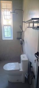 a white bathroom with a toilet and a window at E- Gem in Gulu +7 photos