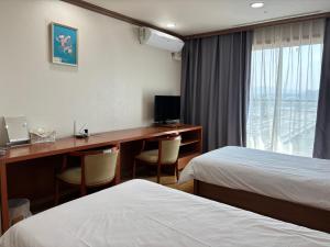a hotel room with two beds and a desk with a computer at Daejeon I-Hotel in Daejeon