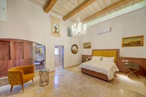 a bedroom with a bed and a chair and a chandelier at Ta Karmenu - A Medieval Maltese Gem 800-Year-Old House near Mdina, Rabat in Rabat