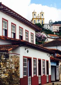 una casa blanca y roja con una iglesia al fondo en Hotel Priskar en Ouro Preto