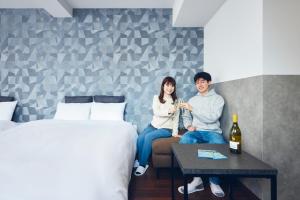 a man and woman sitting on a couch in a hotel room at Montana Wing Yebisu in Osaka