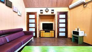 a living room with a purple couch and a tv at Pyeongchang Pension Dorothy in Pyeongchang 