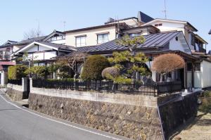 une maison sur un mur de rétention avec une clôture dans l'établissement Minpaku Hiraizumi, à Hiraizumi