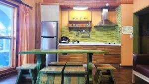 a kitchen with a table and benches and a refrigerator at Pyeongchang Pension Dorothy in Pyeongchang  +4 photos