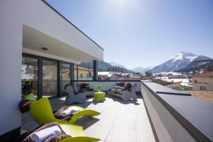 a balcony with people sitting in chairs on a building at Ledermaier Loft & Lodge`s eU in Achenkirch