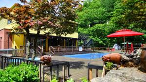 a swimming pool with a red umbrella and a house at Star Light Pension Pet friendly in Gapyeong