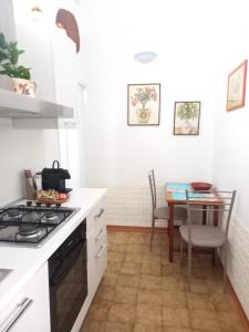 a white kitchen with a table and a stove at M & G - Casa Vacanze in Santa Maria al Bagno