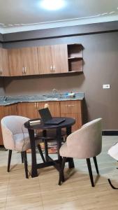 a table with a laptop on it with two chairs at Blaize Affaire Apartments in Kampala