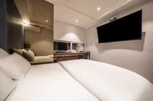 a bedroom with a large white bed and a flat screen tv at No25 Hotel Ansan in Ansan