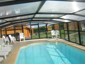 a swimming pool with a pavilion and chairs around it at Gîtes Bon Air in Saint-Flour