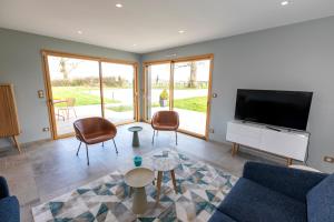 a living room with a tv and a couch and chairs at Chez Watersy in Belle-et-Houllefort