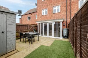 a patio with a table and chairs in front of a building at Comfy & stylish 4 bed house in Bedford