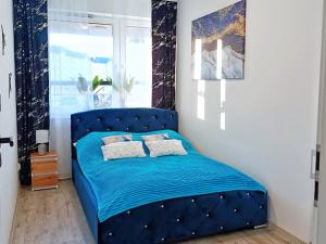 a blue bed in a room with a window at A&R Apartamenty Wenedów III, bezpłatny prywatny parking in Koszalin