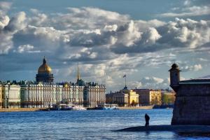 a man standing on the edge of the water in front of a building at Bonjour Hotel in Saint Petersburg