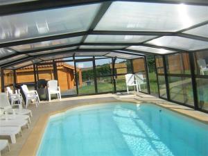 a swimming pool with chairs and a conservatory with at Gîte-Duplex La K-Bane 3 impasse des jardins Piscine et Jacuzzi à 500m in Saint-Flour