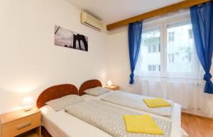 two beds in a bedroom with blue curtains and a window at Young Center in Budapest