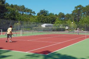 two people playing tennis on a tennis court at Résidence Vacances Bleues Domaine de l'Agréou in Seignosse