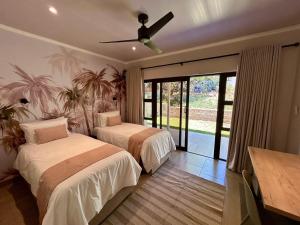 a bedroom with two beds and a ceiling fan at The Musketeers Lodge in Bulawayo