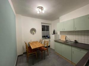 een keuken met een tafel en stoelen en een keuken met witte kasten bij Ferienwohnung Am Wald in Großschönau