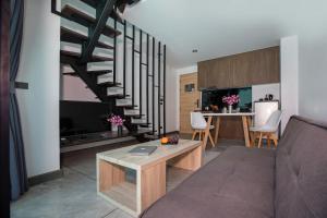 a living room with a couch and a spiral staircase at Poolside Duplex In Nai harn UTL A102 in Rawai Beach
