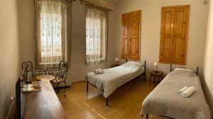 a bedroom with two beds and a table and windows at Chola Guest House in Bitola