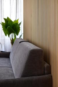 a couch in a room with a plant next to a window at Duomo Imperial Suits - Modern and comfortable in Milan
