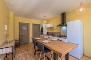 a kitchen with a wooden table and a kitchen with yellow walls at Appartement 2 chambres proche metro et parking in Roubaix