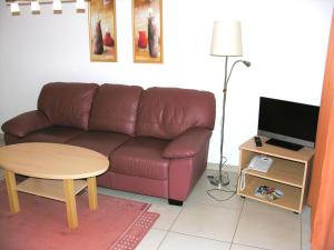 a living room with a brown leather couch and a table at Apartment Am Lübbesee in Templin