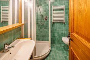 un bagno piastrellato verde con lavandino e doccia di Villa Franchetti - Stayincortina a Cortina dʼAmpezzo