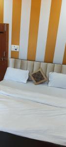 Elle comprend un grand lit avec des draps blancs et des oreillers blancs. dans l'établissement Maa Sharda Guest House, à Ayodhya