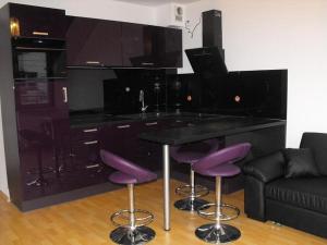 シフィノウイシチェにあるApartment SPAのキッチン(紫色のバースツールと黒いカウンター付)