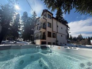 a building with a large swimming pool in front of it at Villa Rila Borovets with Hot Pool, Jacuzzi & Sauna by BookVillaBG in Borovets
