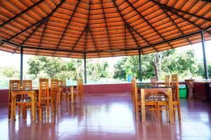 a restaurant with wooden tables and chairs under an umbrella at Trogon resort in Kabini River