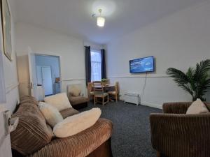 a living room with a couch and a tv on the wall at Nice Living Serviced Accommodations 12 in Coventry