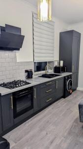 a kitchen with black cabinets and a stove top oven at Crystal Palace Stylish gfloor 1bed apartment,3 minutes walk to Crystal palace station in London +14 photos
