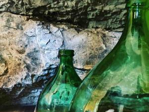 two green glass bottles sitting next to a stone wall at La grotte Dinant in Dinant